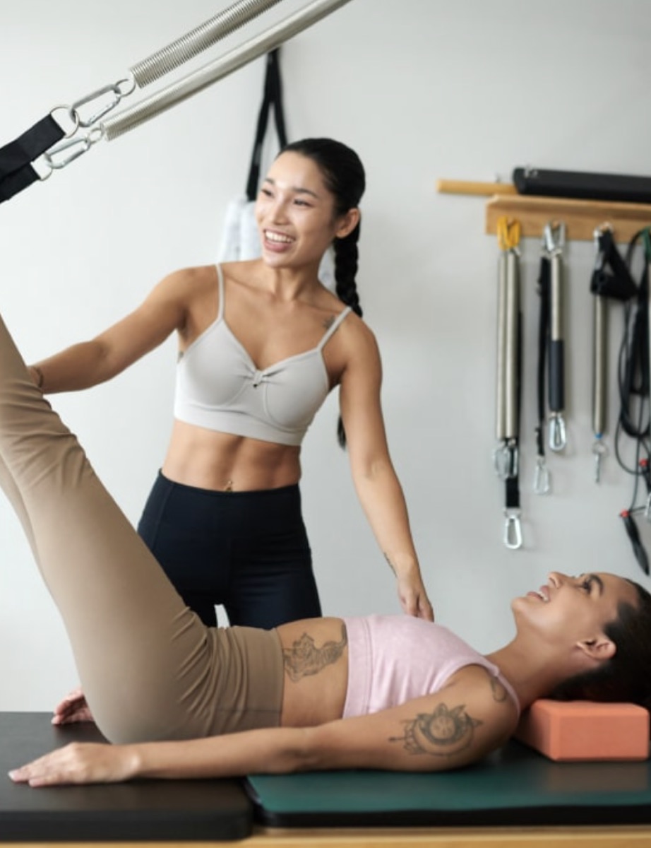 An instructor guiding a client on a Pilates reformer